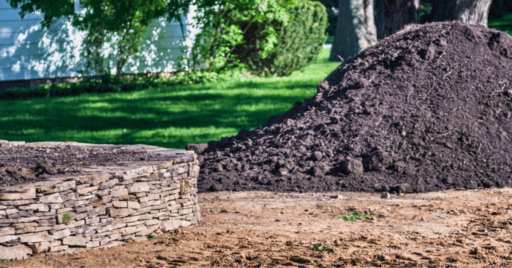 mound of delivered topsoil next to stone wall