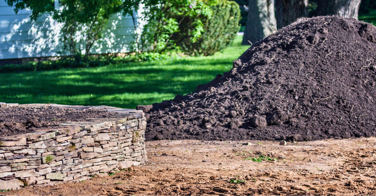 mound of delivered topsoil next to stone wall