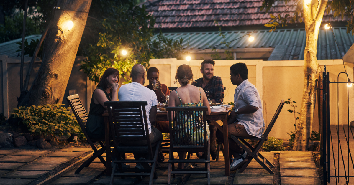 A group of young adults enjoying a summer night on a modern back patio.